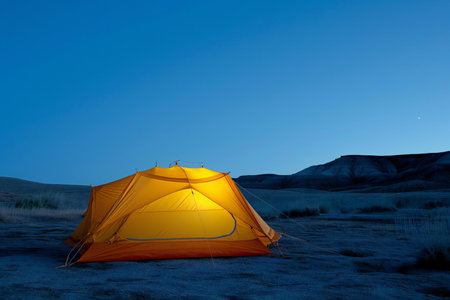 Camping tent at sunset in the desert with blue sky background.の素材