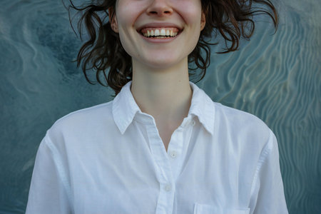 Young woman in a white shirt smiles and looks at the camera.の素材