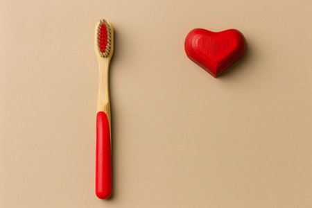 Two wooden toothbrushes and red heart on beige background.の素材