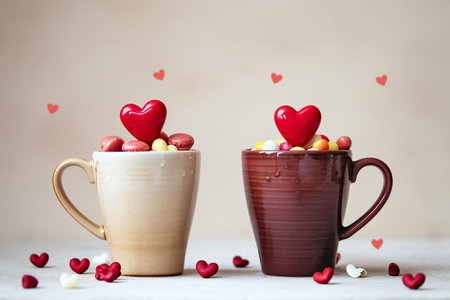 Two cups of coffee with candies in the form of hearts on a light backgroundの素材