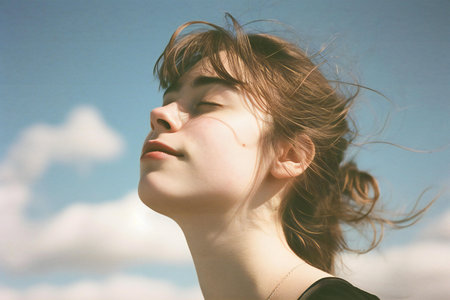 Portrait of a young beautiful girl with windy hair against the skyの素材