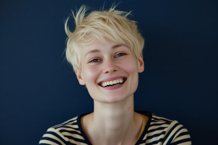 Portrait of a smiling blond boy on a dark blue background.の素材
