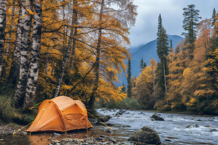 Orange tent in the middle of a mountain river in the autumn forestの素材