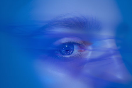 blue eye of a young woman close-up in the blue lightの素材