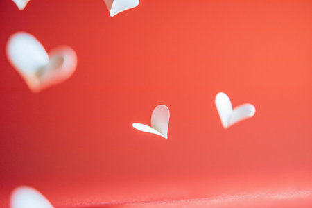 White paper hearts on a red background. Valentines day background.の素材