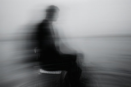 abstract blurred image of a man sitting on a bench in the rainの素材