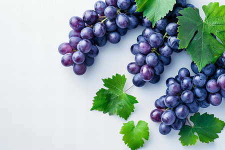Bunch of fresh grapes with green leaves on a white background.