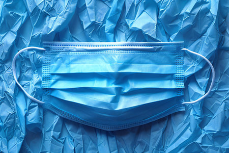 Blue surgical mask on a blue background. Coronavirus concept.