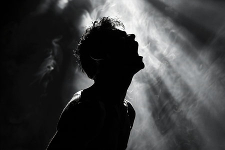 Silhouette of a young woman on a dark background with rays of light