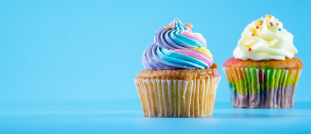 Colorful and enteresting cupcake isolated on blue background studio close up shot.