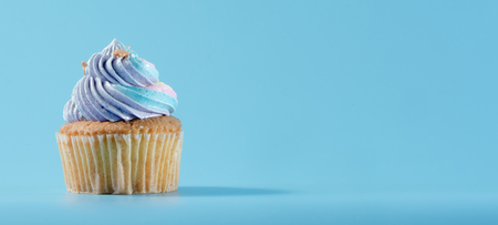 Colorful and enteresting cupcake isolated on blue background studio close up shot.の写真素材