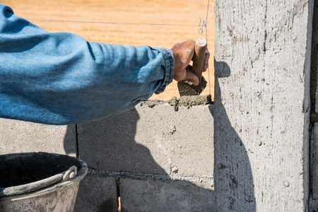 Worker making concrete wall by plaster and cement block at construction site