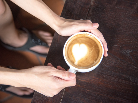hand holding coffee cup  on the wooden tableの写真素材