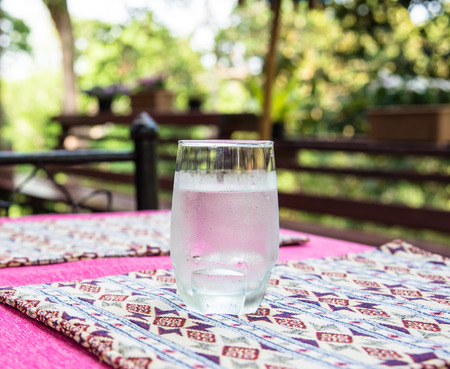 Glass of cold water put on  table mat in the out door resortの写真素材