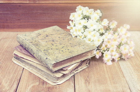 old diary book put on the wood floor together with flower . effected by ray of light from top right corner.の写真素材