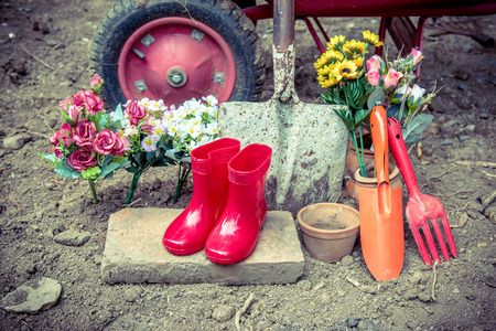 gardening tool including by red boots vase , fork , shovel and barrow , vintage color tone effectの写真素材