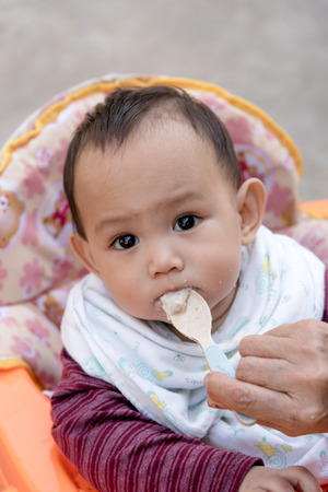 Baby eating food by mother feeding, family scene of Thailandの写真素材