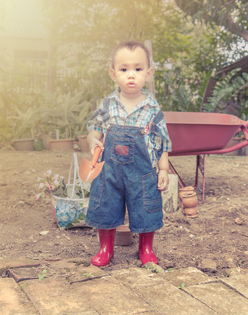 Baby gardener. Asian baby boy handle garden spoon , light and vintage color effectの写真素材