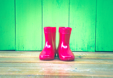 red color children boot on the wood floor and green wood backgroundの写真素材