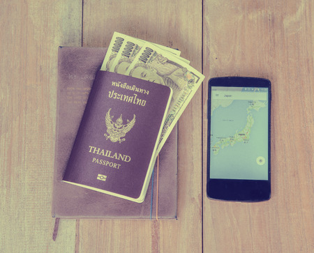 Japan money insert in Thai passport put on brown color note book with old smart phone which open Japan map, Traveler concept and vintage color tone effectの写真素材