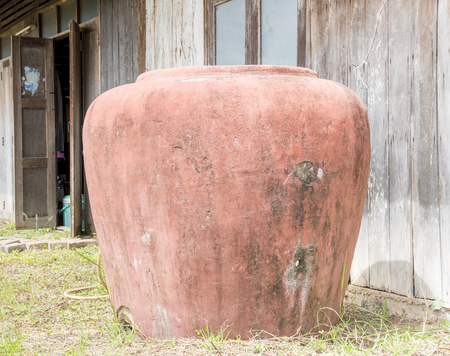 Red color big water jar , Thai people use as water tank to keep rainwater in raining seasonの写真素材
