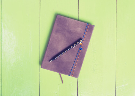 Top view of notebook and pen put on green color wood boardの写真素材