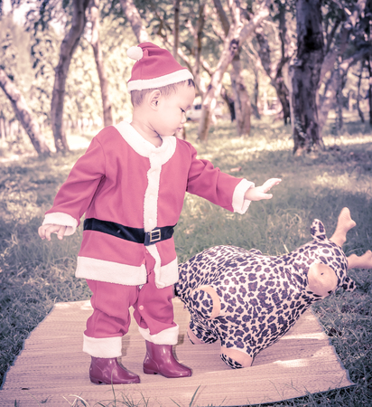 A kid in Santaclaus suit push reindeer doll away , unfriend concept  and black and white photography with vignetteの写真素材