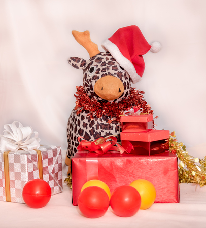Kid in the red Santa Claus suit sitting with reindeer doll among the gift boxesの写真素材