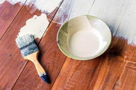 Paint brush and  bowl  of white coating color put on wood board, top view of brush and bowl with white coating colorの写真素材