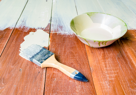 Paint brush and  bowl  of white coating color put on wood board, top view of brush and bowl with white coating colorの写真素材