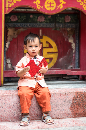Asian baby boy hold red envelope or Ang-pow . The kid smiling because of  feeling   happiness from a  Chinese new year gift .の写真素材