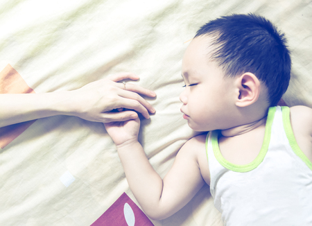 Asian mother holding baby hand while sleeping , Lovely Thai familyの写真素材