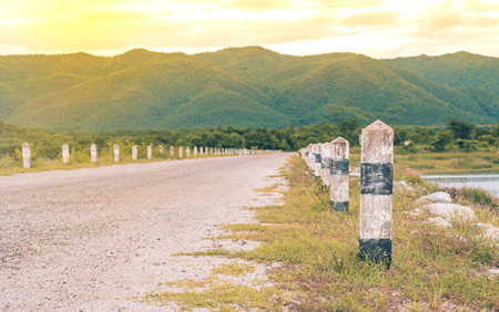 Rural road to mountain with concrete barrier in evening timeの写真素材