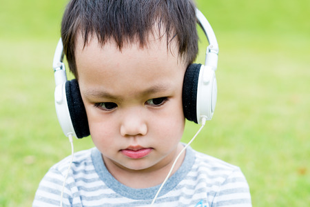 Asian baby boy listening music by headphoneの写真素材