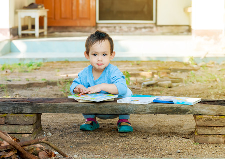 Asian baby boy reading tale book alone at outdoorの写真素材