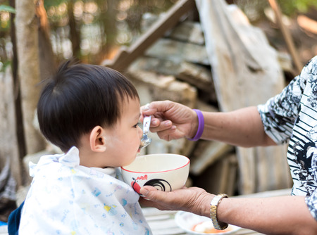 Asian baby boy  feeding food by grand momの写真素材