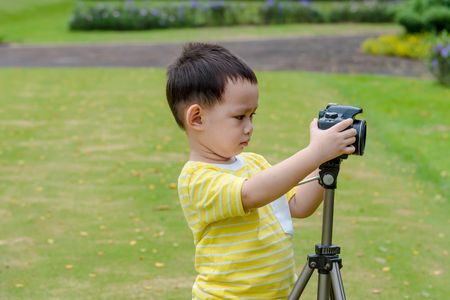 Asian baby boy taking photo graphy in nature by DSLR camera and tripodsの写真素材