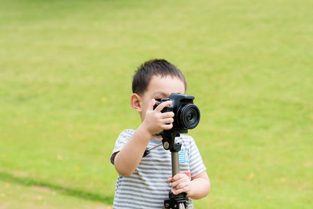 Asian baby boy taking photo graphy in nature by DSLR camera and tripodsの写真素材