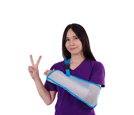 Asian lady in purple T shirt wearing arm sling . Her arm swathe  by elastic bandage. with clipping pathの写真素材