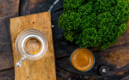 Espresso coffee cup serve with glass of water on wooden table which decor by green plant