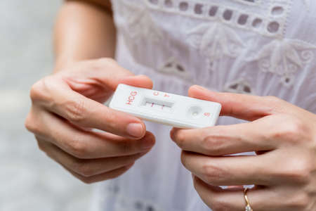 Lady in white dress Hand holding pregnancy testerの写真素材