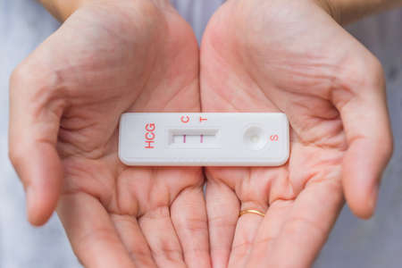 Lady in white dress Hand holding pregnancy testerの写真素材