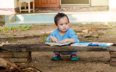 Asian baby boy reading tale book alone at outdoorの写真素材