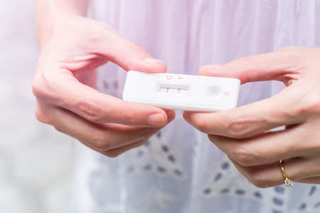 Lady in white dress Hand holding pregnancy testerの写真素材