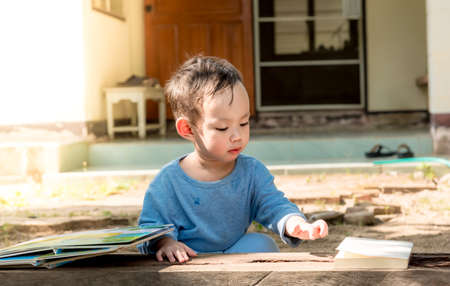 Asian baby boy reading tale book alone at outdoorの写真素材
