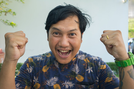 Successful Asian tattoos man raising arms celebrating success and goals .の写真素材