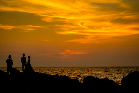 Silhouette couple's taking a photo prewedding before sunset on the beach rock , Phuket Thailand.の写真素材