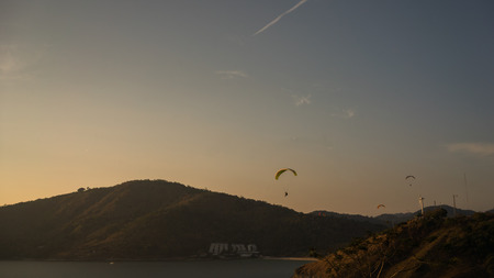 Beautiful island landscape paraglider flying over sea at the sunset time of Phuket, Thailandの写真素材