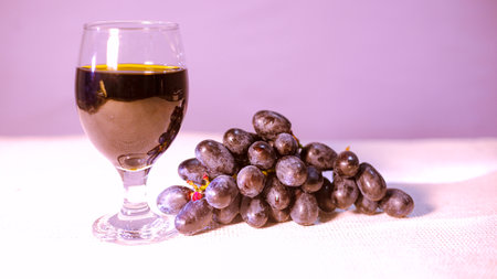 Glass of tasty dark wine and bunch of black grapes isolated on Purple background, side viewの写真素材