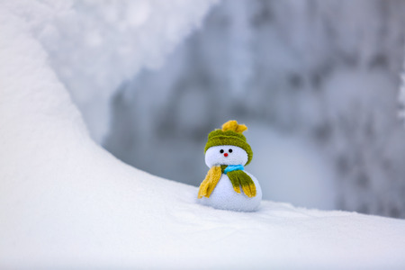 On the white fluffy textured snow alone snowman the friend is standing in nice hat and scarf with...